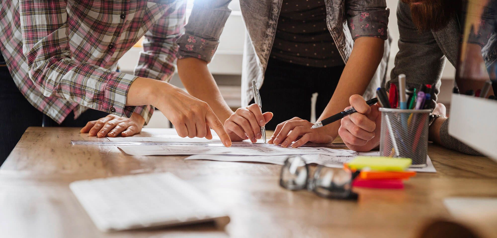 A Team Of People Surrounding A Desk Working