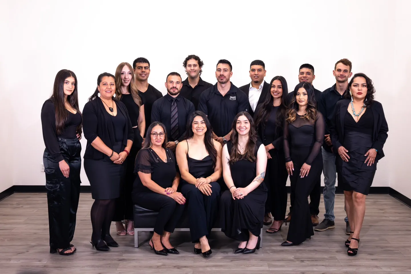 Group of diverse professionals dressed in black formal attire posing in an office setting for a team photo
