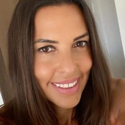 Close-up of a young woman with long brown hair smiling at the camera