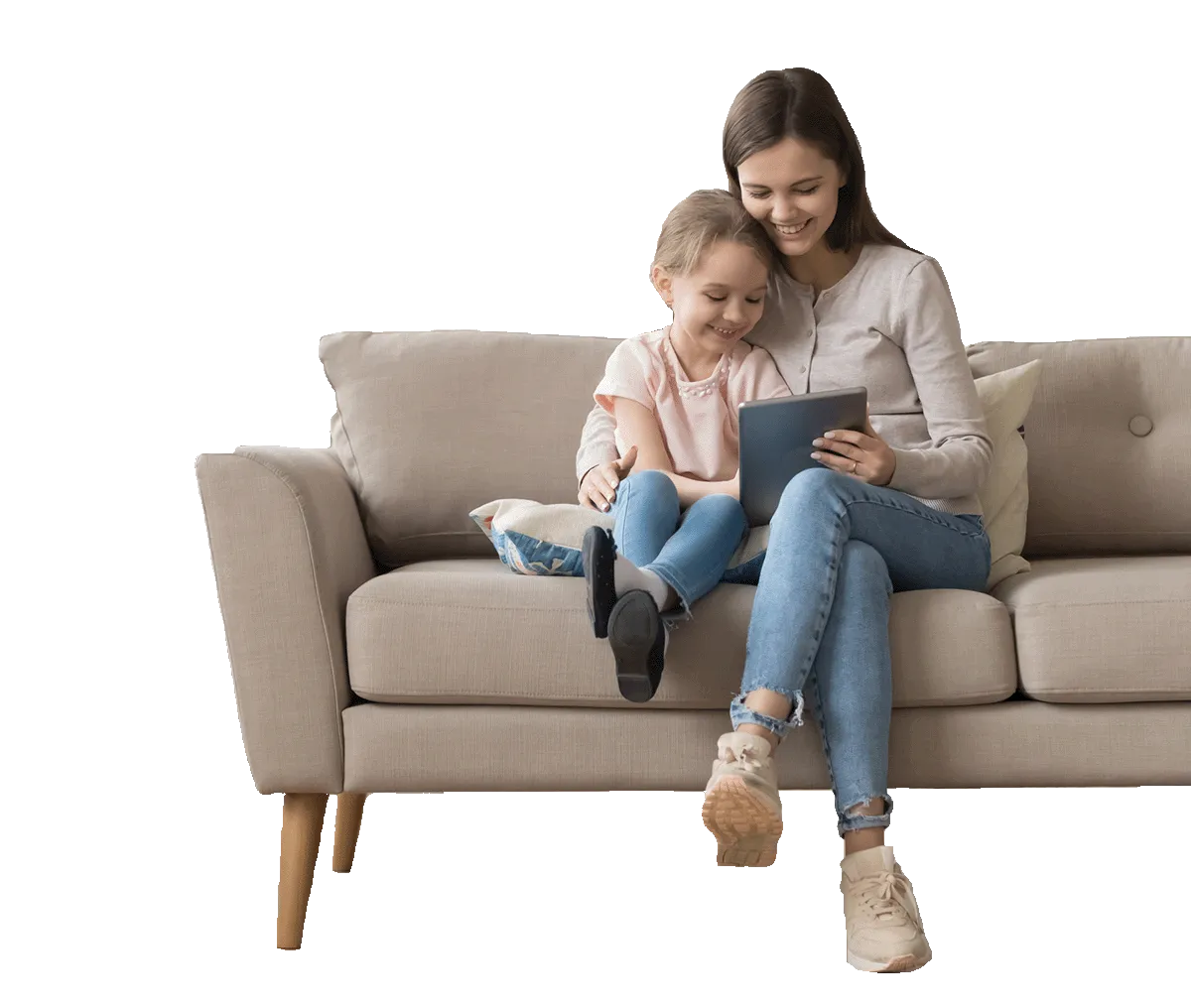 Mother and daughter sitting on a beige sofa, looking at a tablet together and smiling.