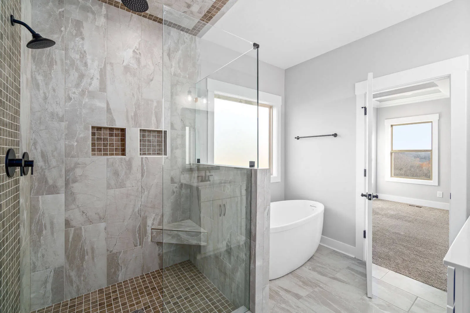 Modern bathroom with a walk-in shower, freestanding bathtub, and large windows overlooking scenic views