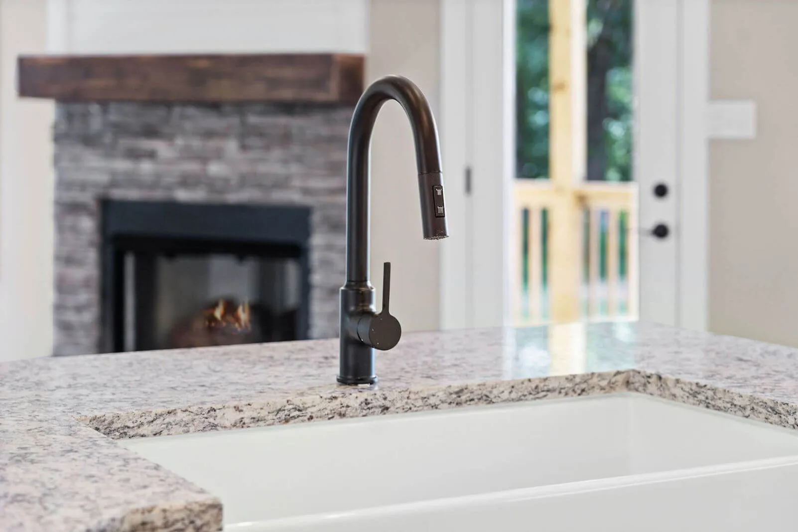 Modern black kitchen faucet installed on a granite countertop with a white undermount sink in a contemporary kitchen interior.