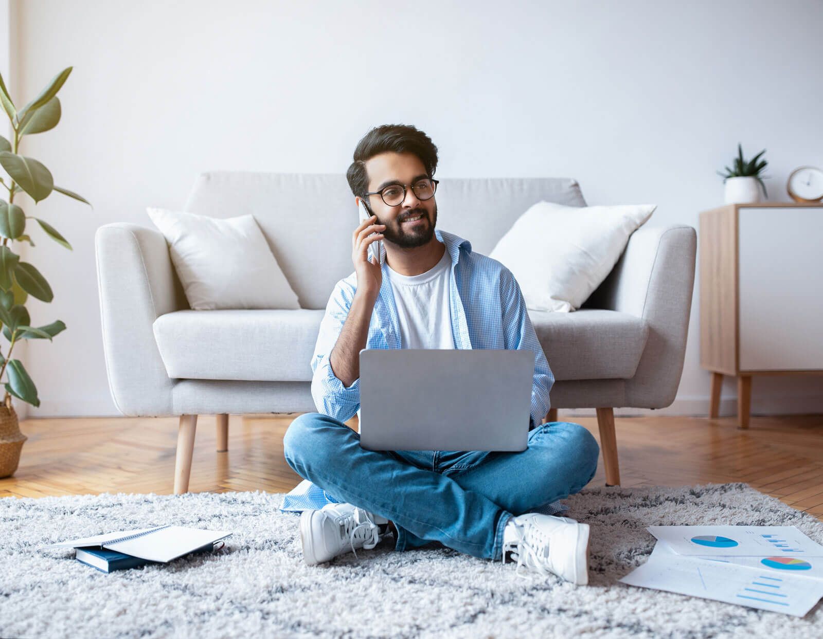 Guy sitting on ground with laptop makes phone calls