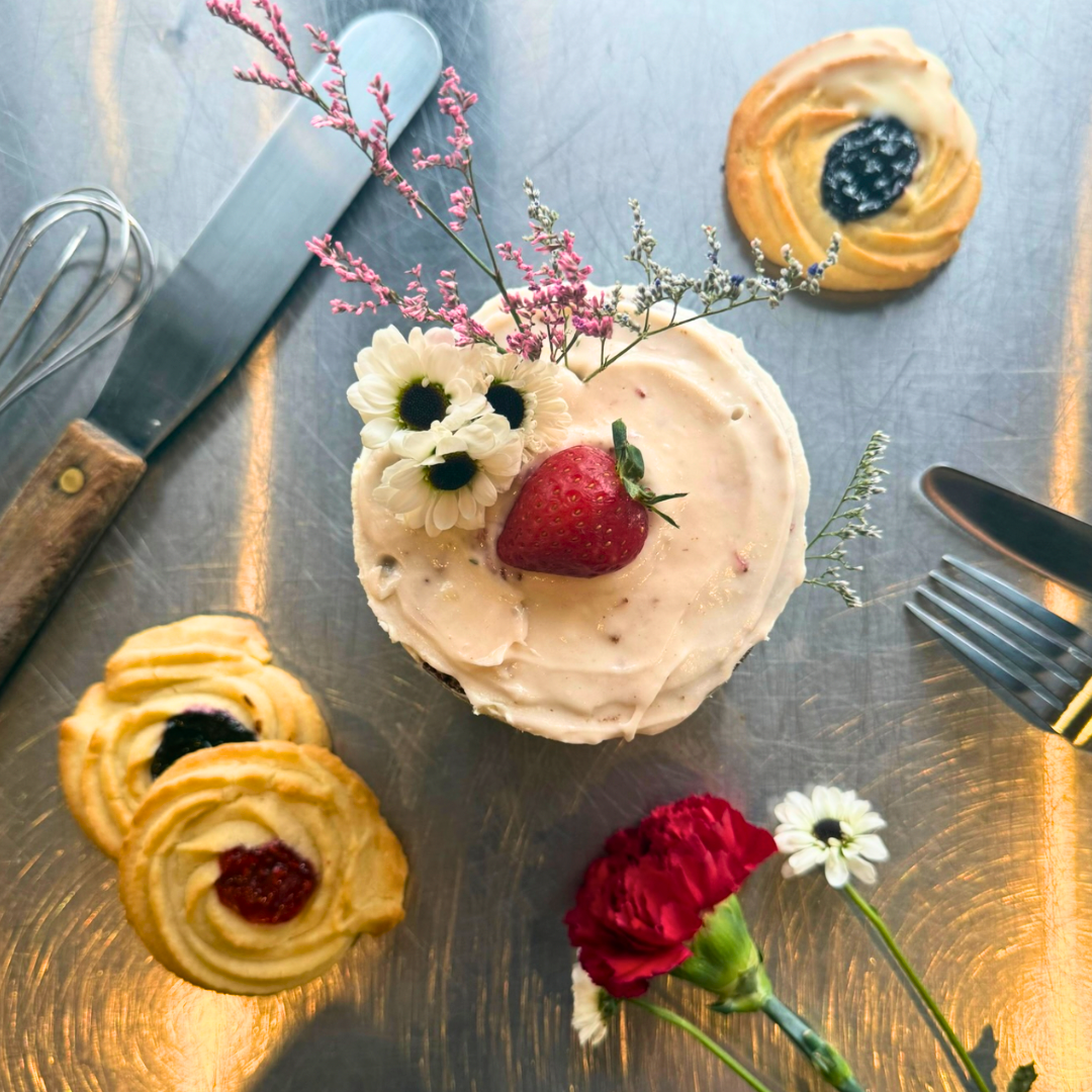 Plate with hamburger, French fries, lettuce, tomato, and onion sandwich with side of French fries on a white table, accompanied by a glass of dark soda, ketchup, and salt and pepper shakers.