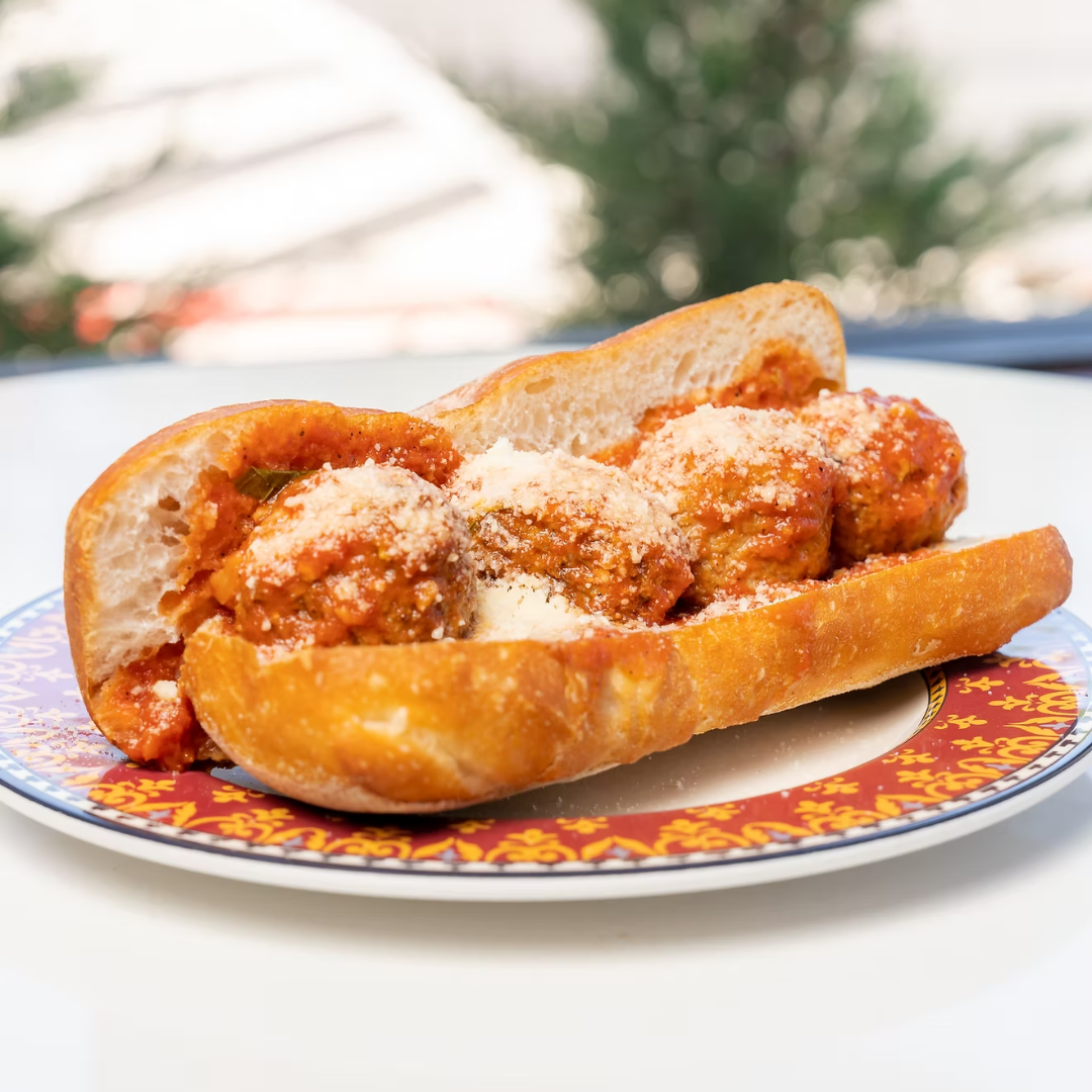 Plate with hamburger, French fries, lettuce, tomato, and onion sandwich with side of French fries on a white table, accompanied by a glass of dark soda, ketchup, and salt and pepper shakers.