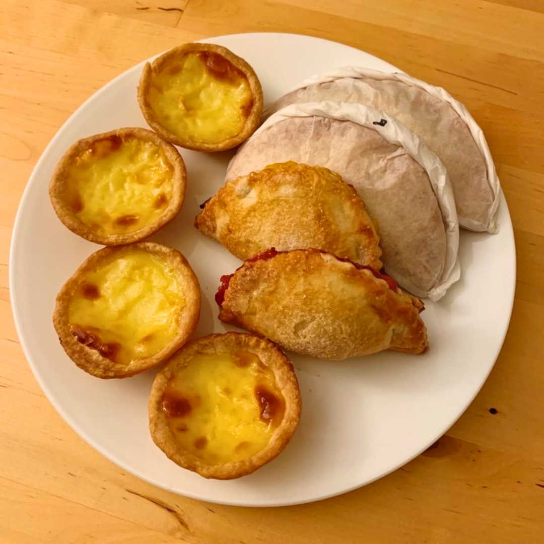 Plate with hamburger, French fries, lettuce, tomato, and onion sandwich with side of French fries on a white table, accompanied by a glass of dark soda, ketchup, and salt and pepper shakers.