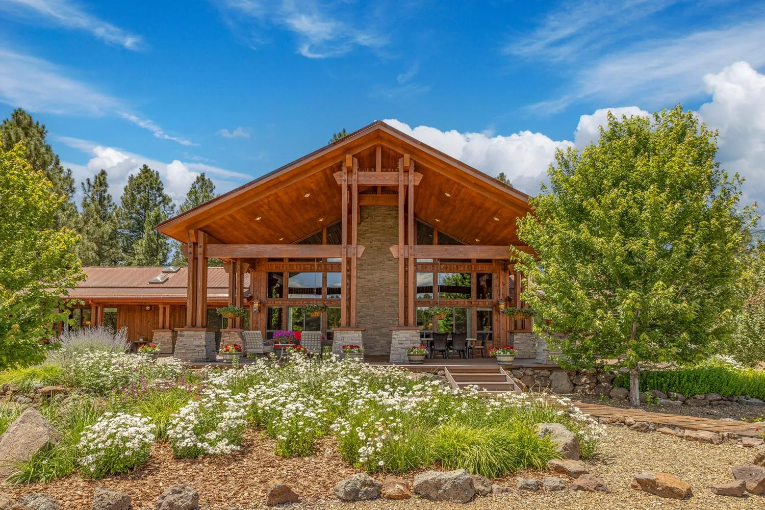 Rustic dining room with wooden floors, stone fireplace, cozy windows, and natural light, connecting to the kitchen.