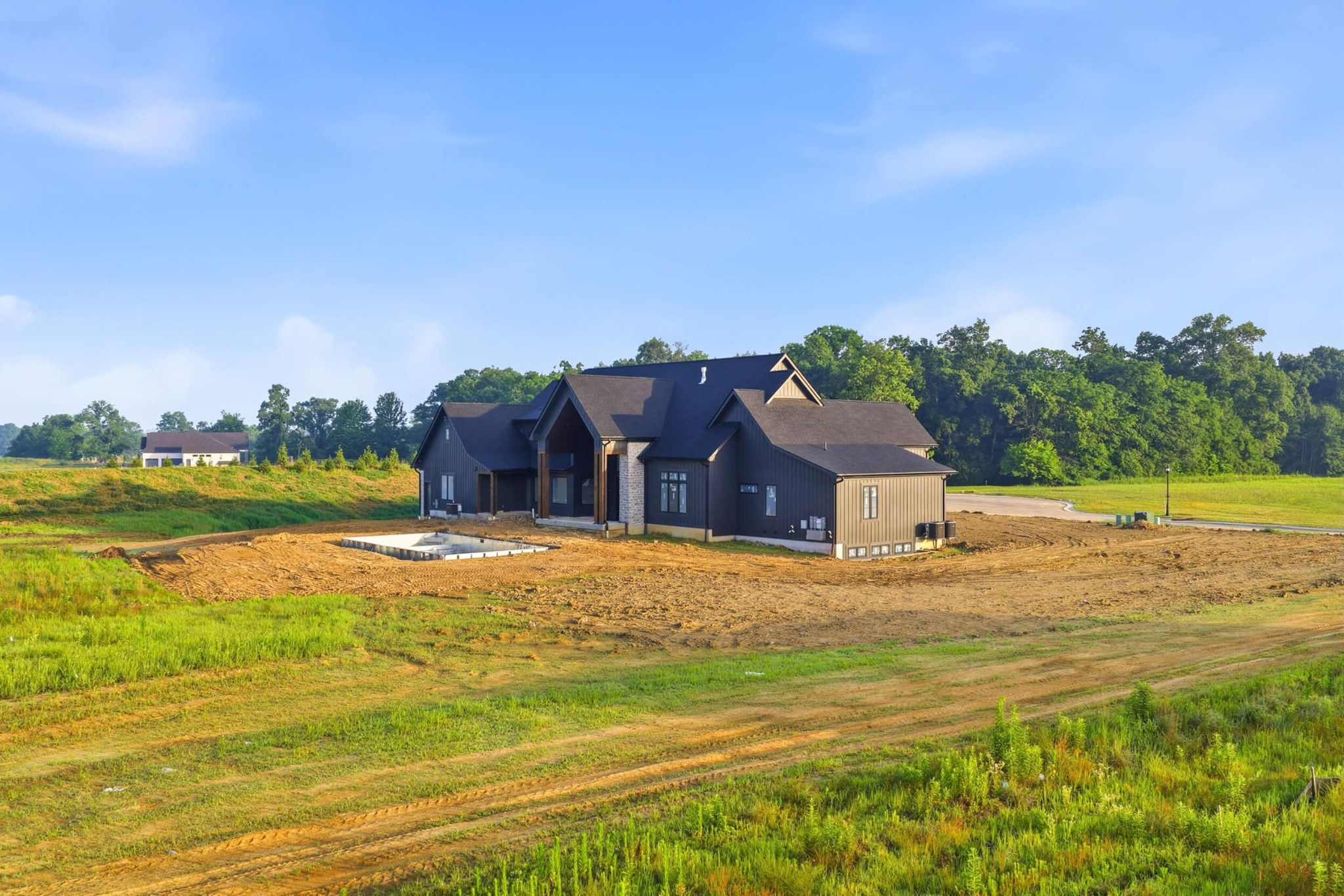 Side exterior view with pool excavation and pond in the distance