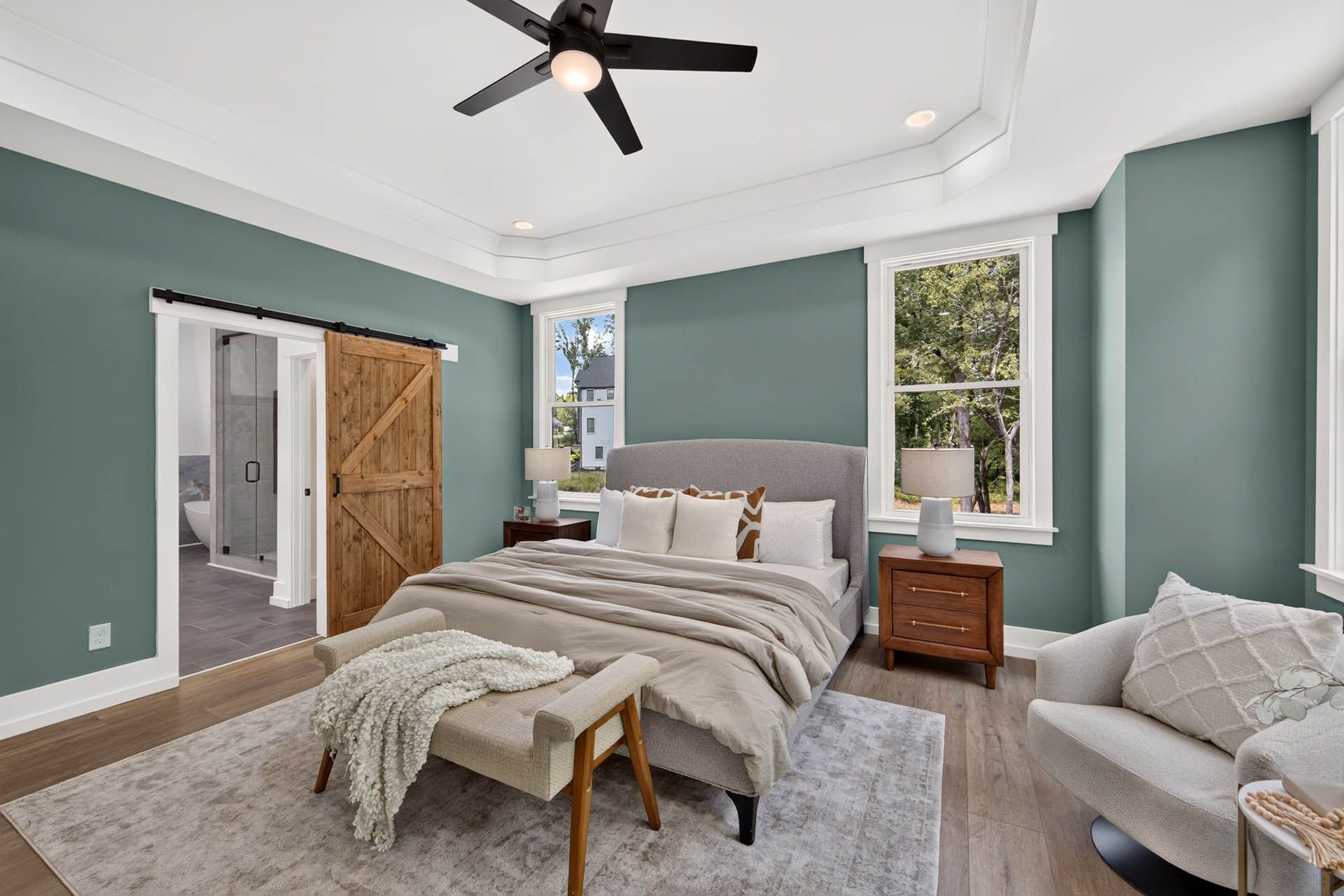 Primary bedroom with tray ceiling and sliding barn door to the bath