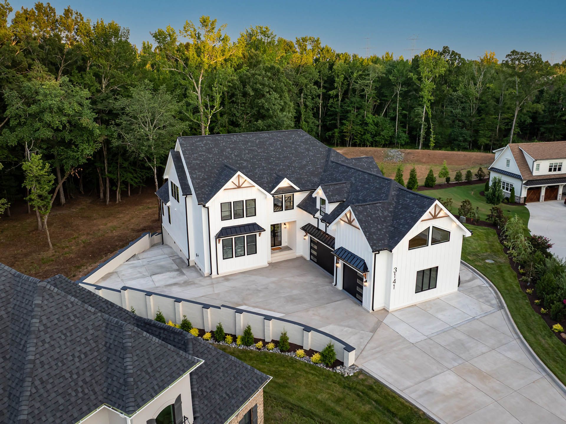 Twilight aerial view of the home and surrounding trees