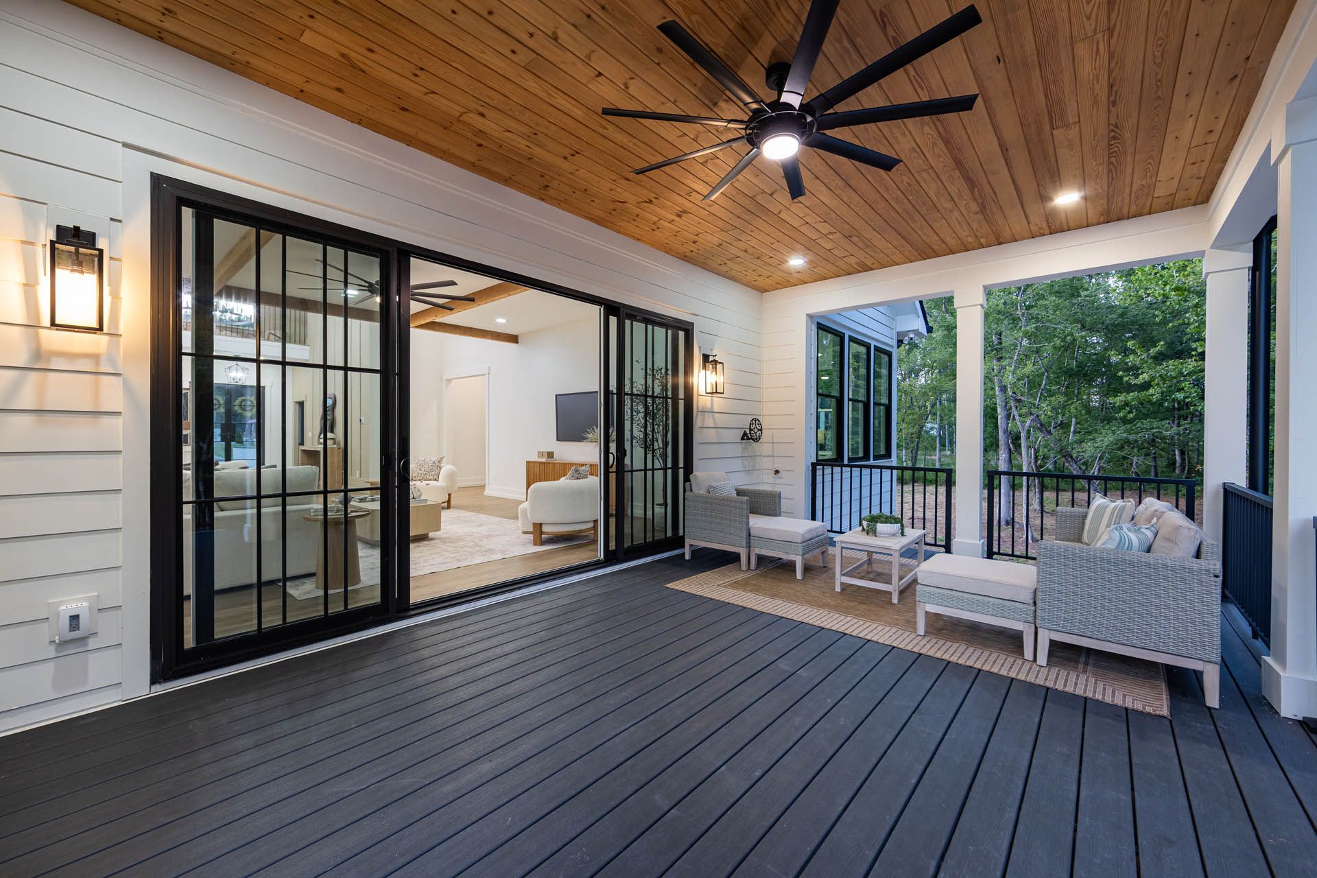 Covered upper deck with outdoor seating overlooking the wooded lot