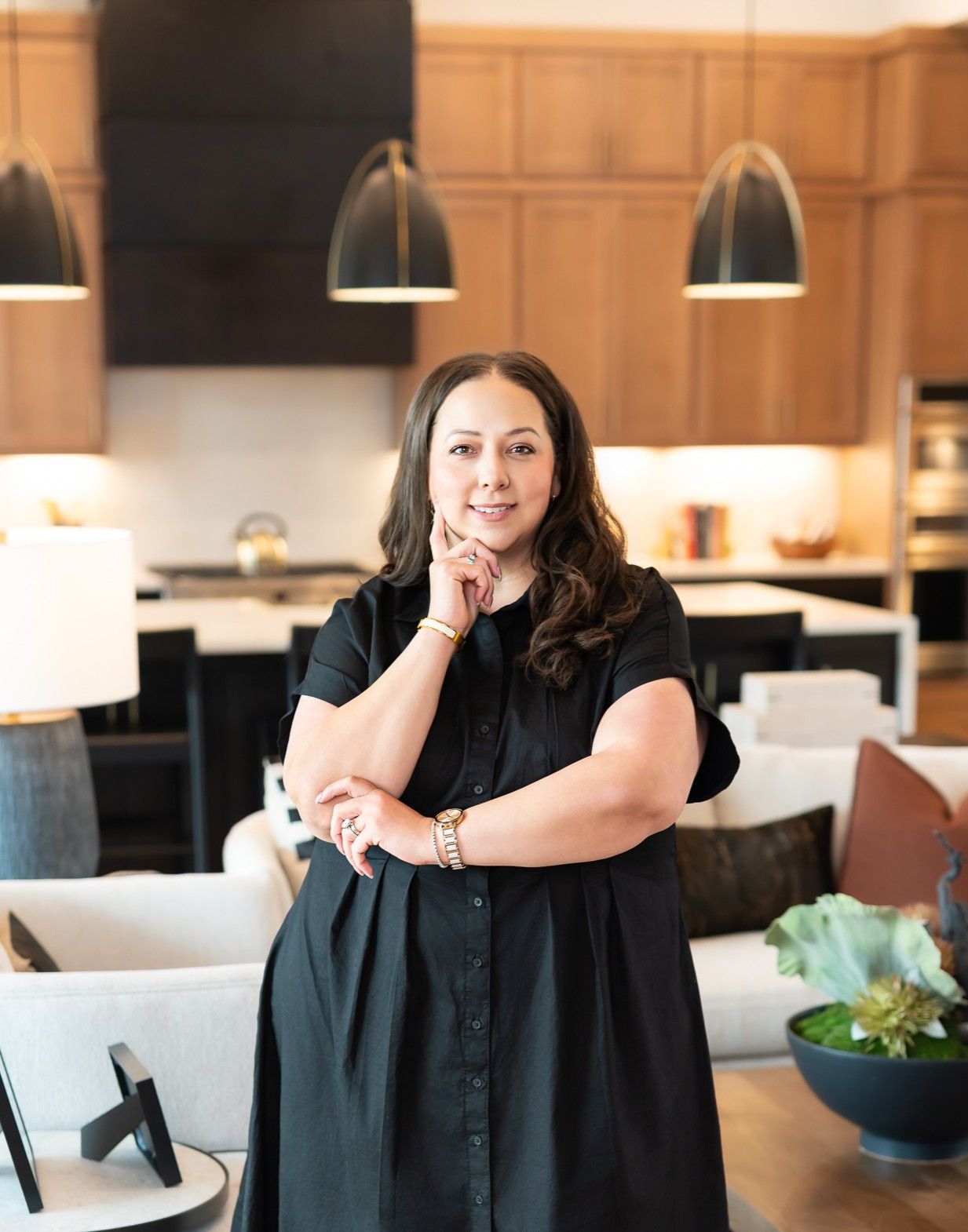 A woman in a black buttoned dress standing inside a home.