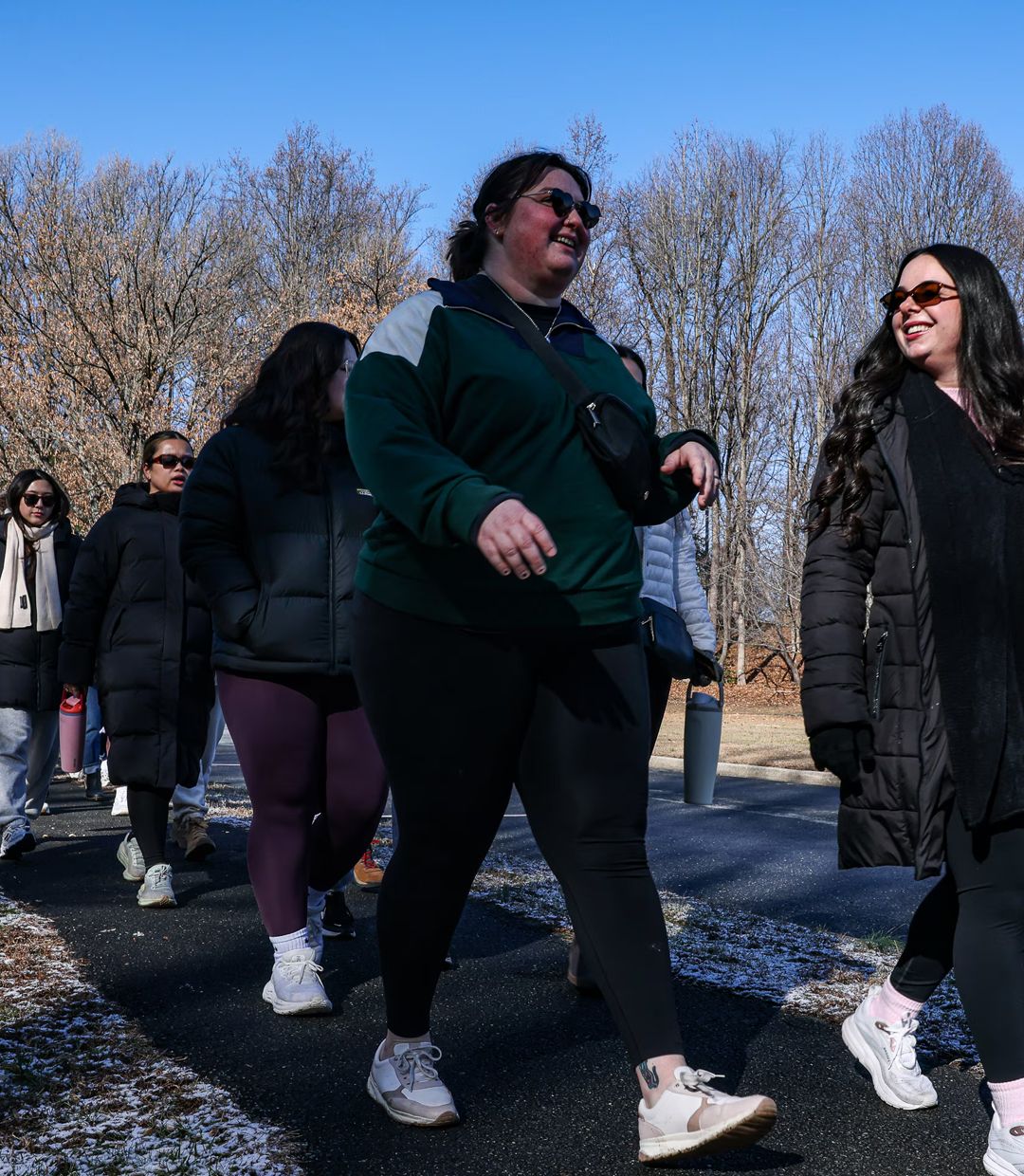 Fresh organic heirloom tomatoes, yellow and red cherry tomatoes, and green zucchinis displayed at a farmer's market in a woven basket and plastic containers.