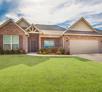 Beautiful modern brick and siding suburban house with well-maintained front lawn and attached garage under a partly cloudy sky