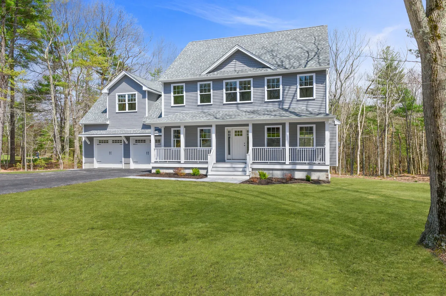 Modern two-story house with a gray exterior, large windows, and a double garage with a white door in a suburban neighborhood