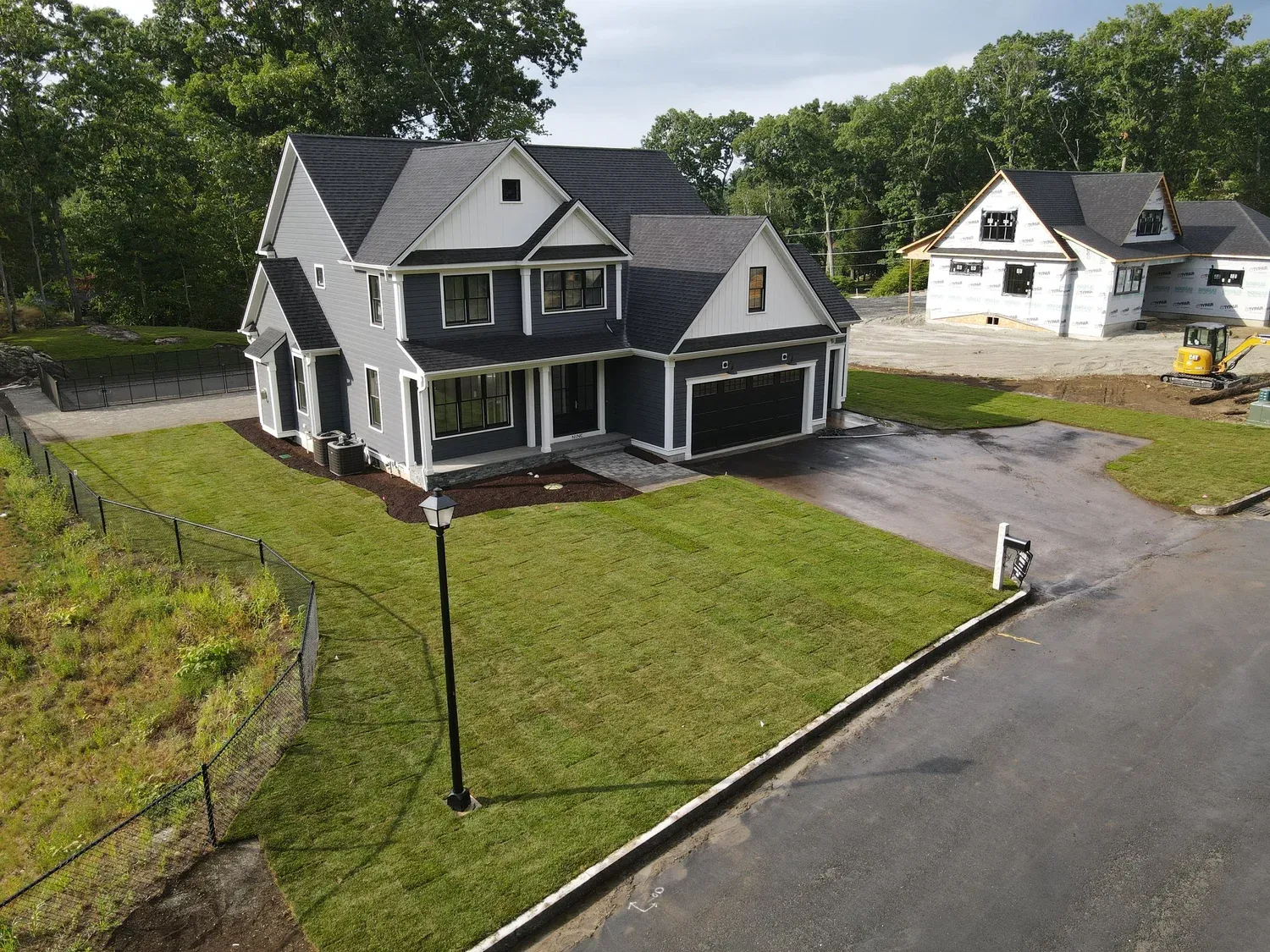New two-story house under construction with exterior sheathing and framing in progress, located in a suburban neighborhood.