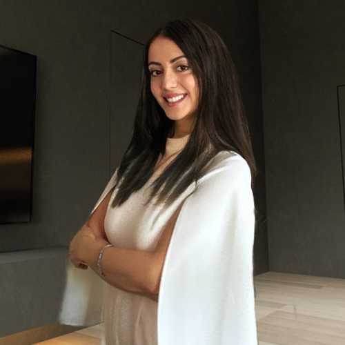 Young woman with long dark hair smiling in professional attire in modern office setting