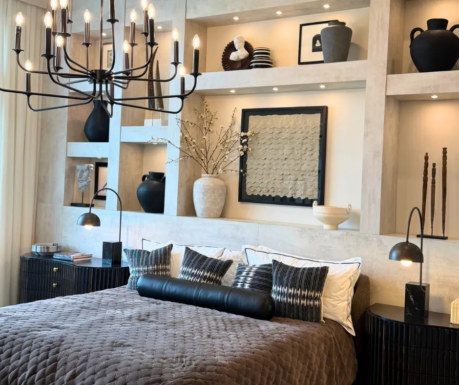 Bedroom in an Apex at Avenir model home with a black chandelier, upholstered bed and built-in display shelving.