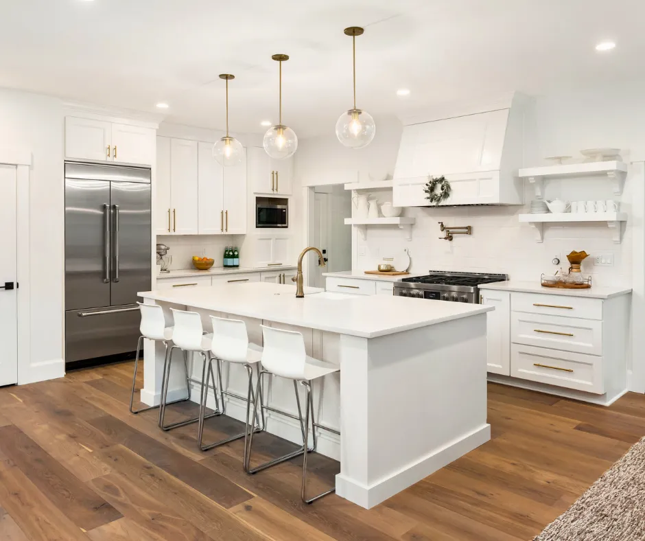 White kitchen with large island, pendant lights, wood flooring and stainless steel appliances in Windgate at Avenir