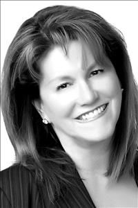 Smiling woman with shoulder-length hair wearing a dark blazer, black-and-white portrait