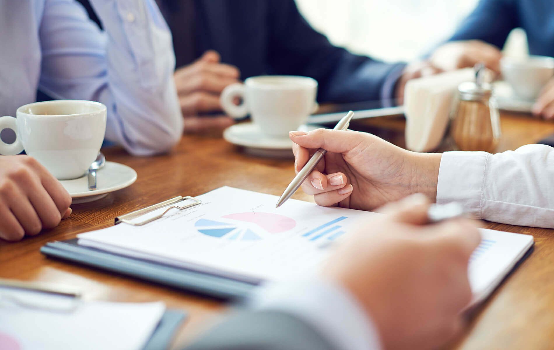 Business meeting discussing financial reports with coffee on a wooden table