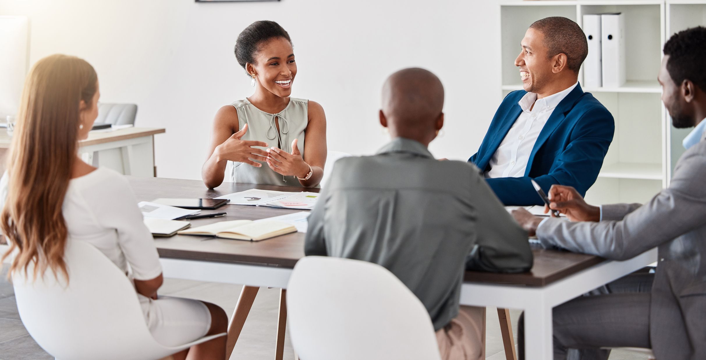 Group of diverse professionals at a real estate event posing in front of a 