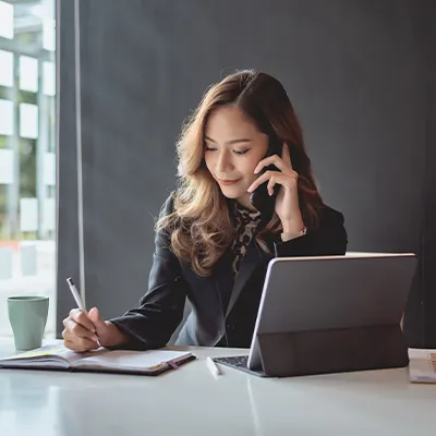 Businesswoman working on a laptop and talking on the phone in a modern office setting