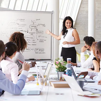 Businesswoman giving presentation and market analysis to diverse team in modern conference room