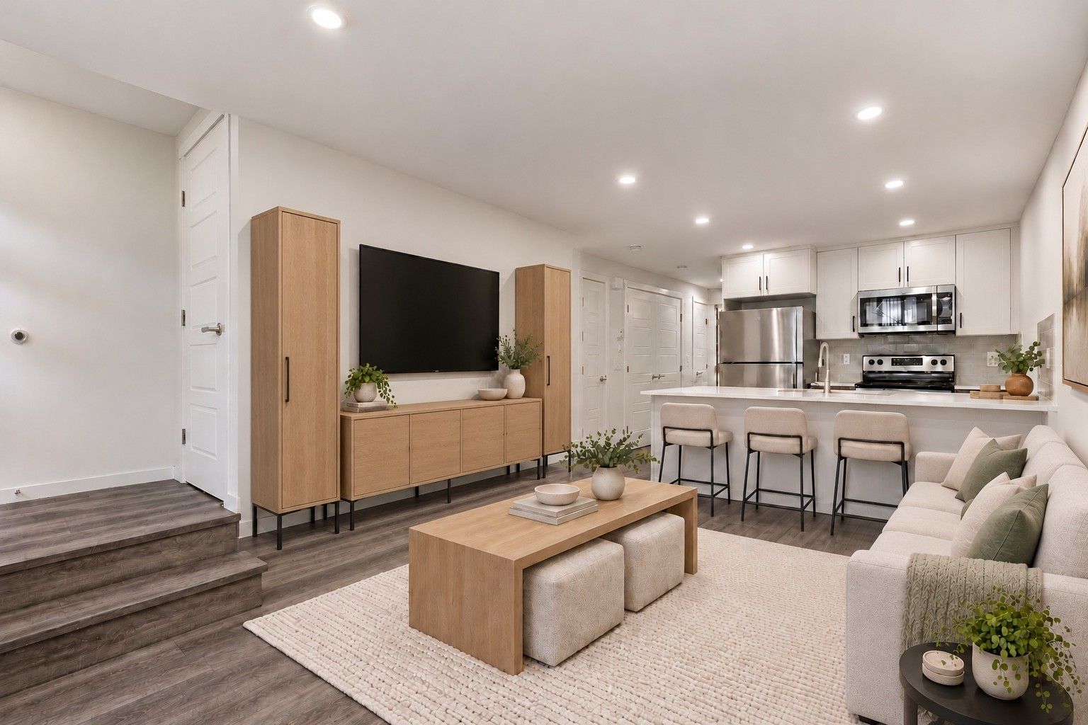 Virtually staged living room with TV wall open to a white shaker kitchen with white quartz peninsula and breakfast bar at 113, 40 Livingston Parade NE, ZEN Livingston, Calgary