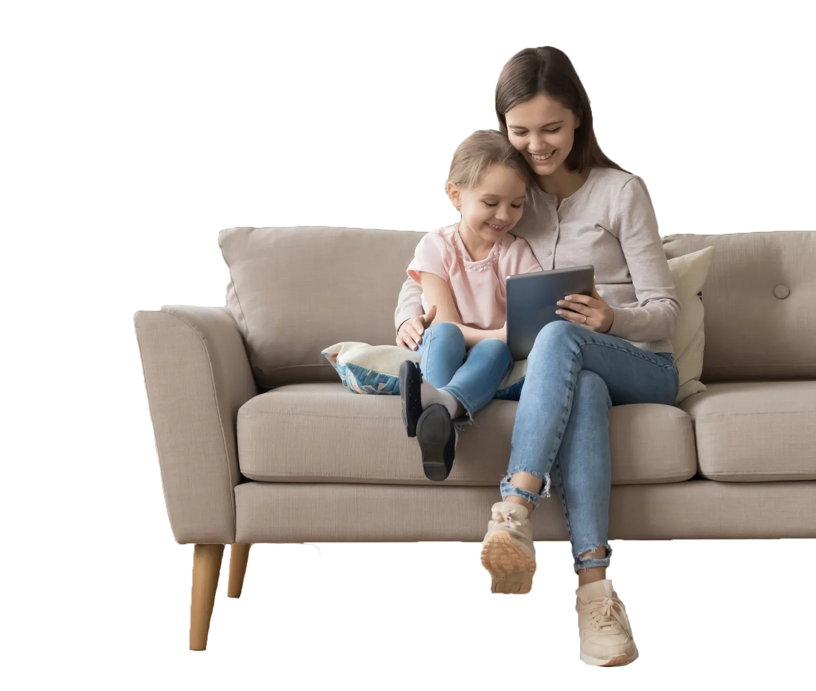 Mother and daughter sitting on a beige sofa, looking at a tablet together, smiling, with the daughter wearing a pink shirt and blue jeans, and the mother in a light gray top and blue jeans.