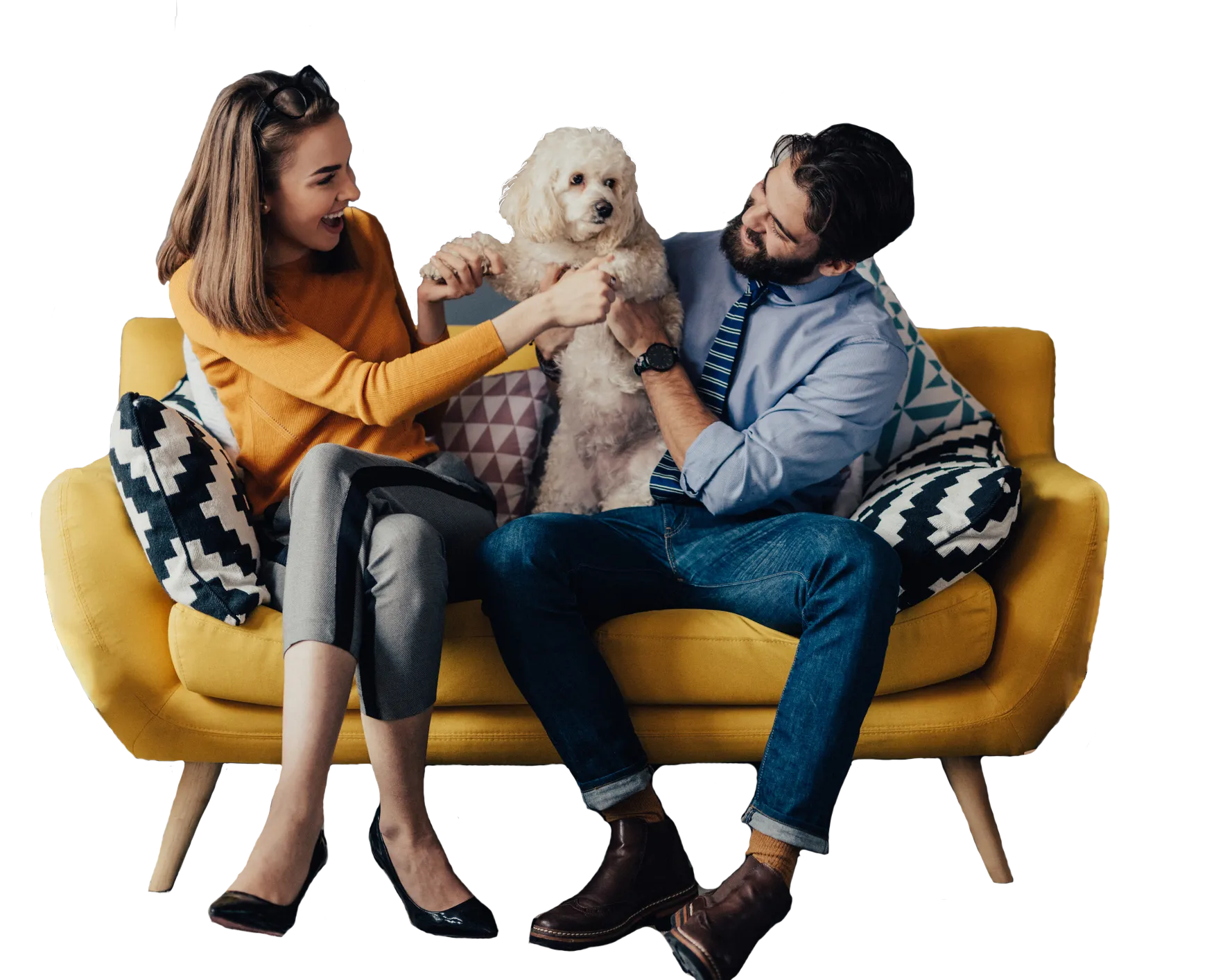 Happy couple playing with a white fluffy dog on a yellow sofa with patterned cushions.