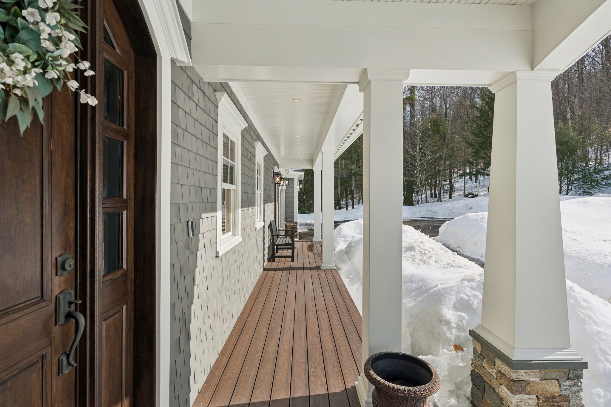 Front view of a two-story suburban house with a three-car garage, surrounded by greenery and trees, with a paved driveway, a basketball hoop, and a landscaped front yard.