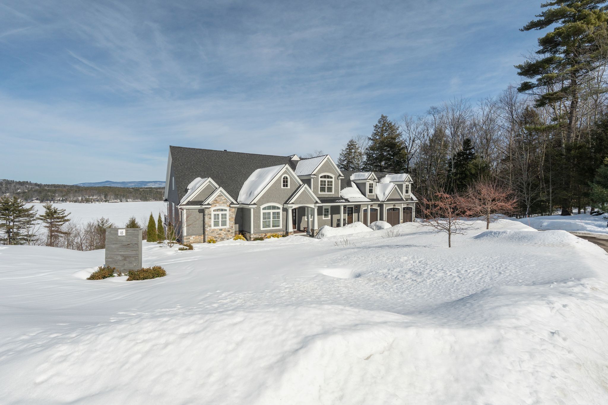 Beautiful suburban backyard with lush green lawn, mature trees, and a house with a garage and basketball hoop in the background