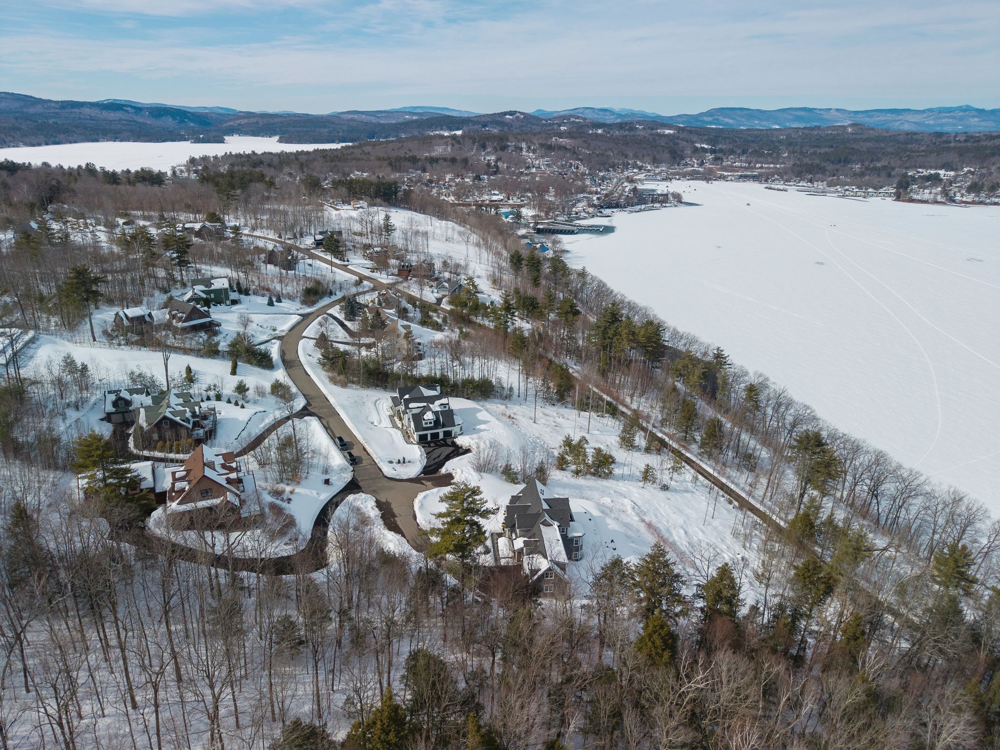 backyard outdoor patio with seating and barbecue grill, overlooking a scenic landscape with trees, lake, and hills in the distance