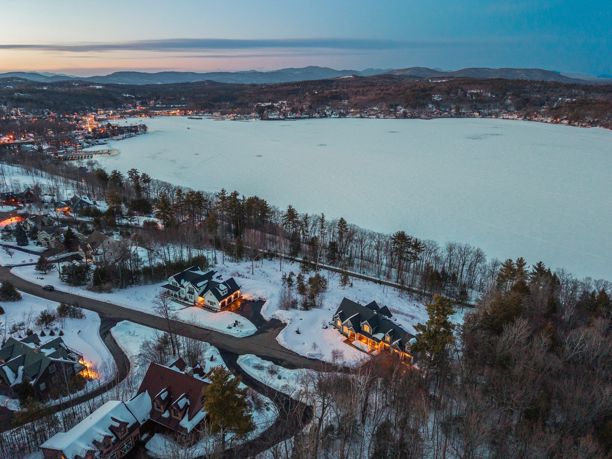 Wooden gazebo with round table and Adirondack chairs overlooking lush green trees in a backyard.