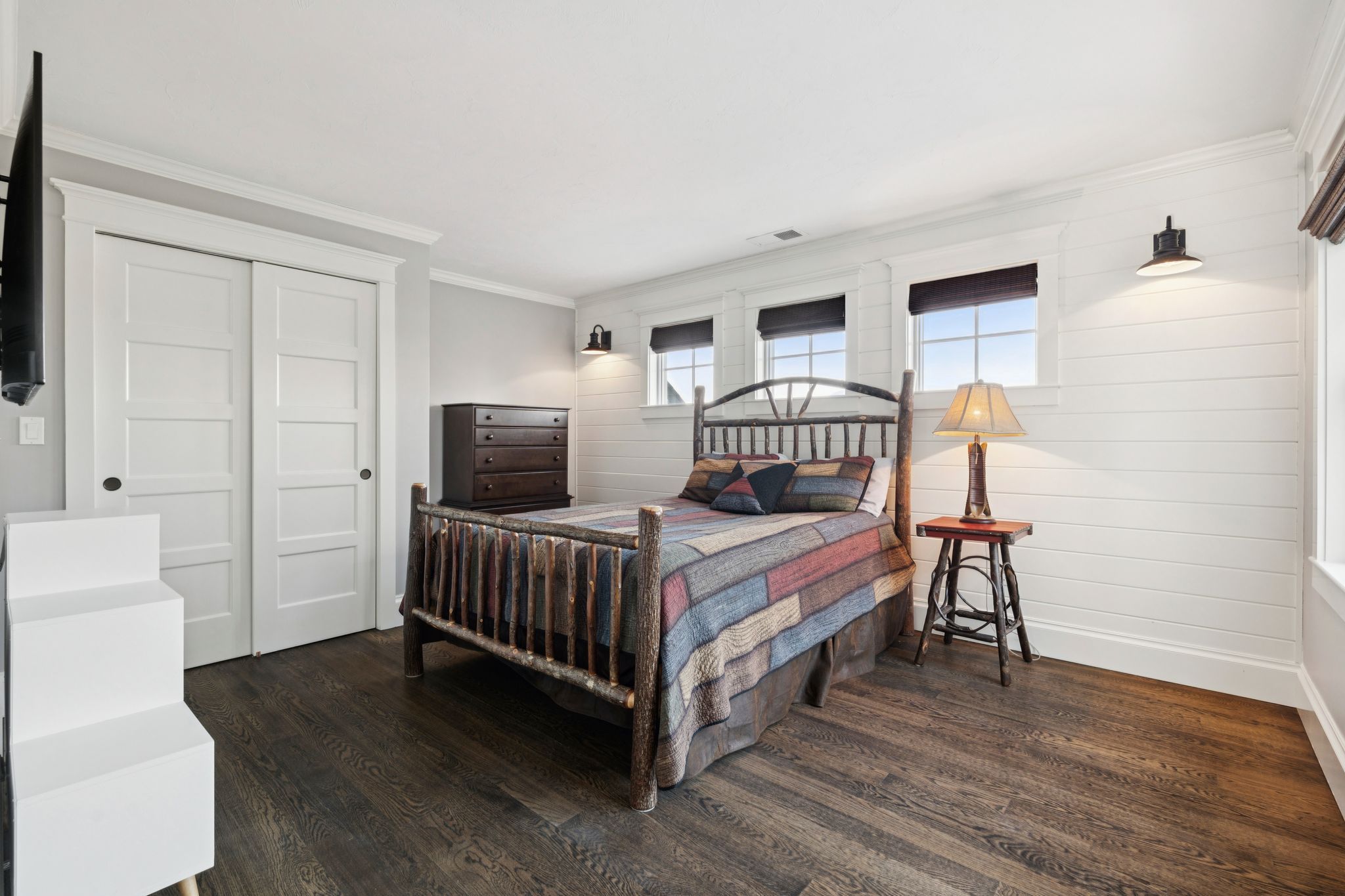 Modern bathroom featuring a glass-enclosed shower with decorative tile accent, a jacuzzi tub with a potted plant and artwork, and a double vanity with round mirrors and contemporary lighting.