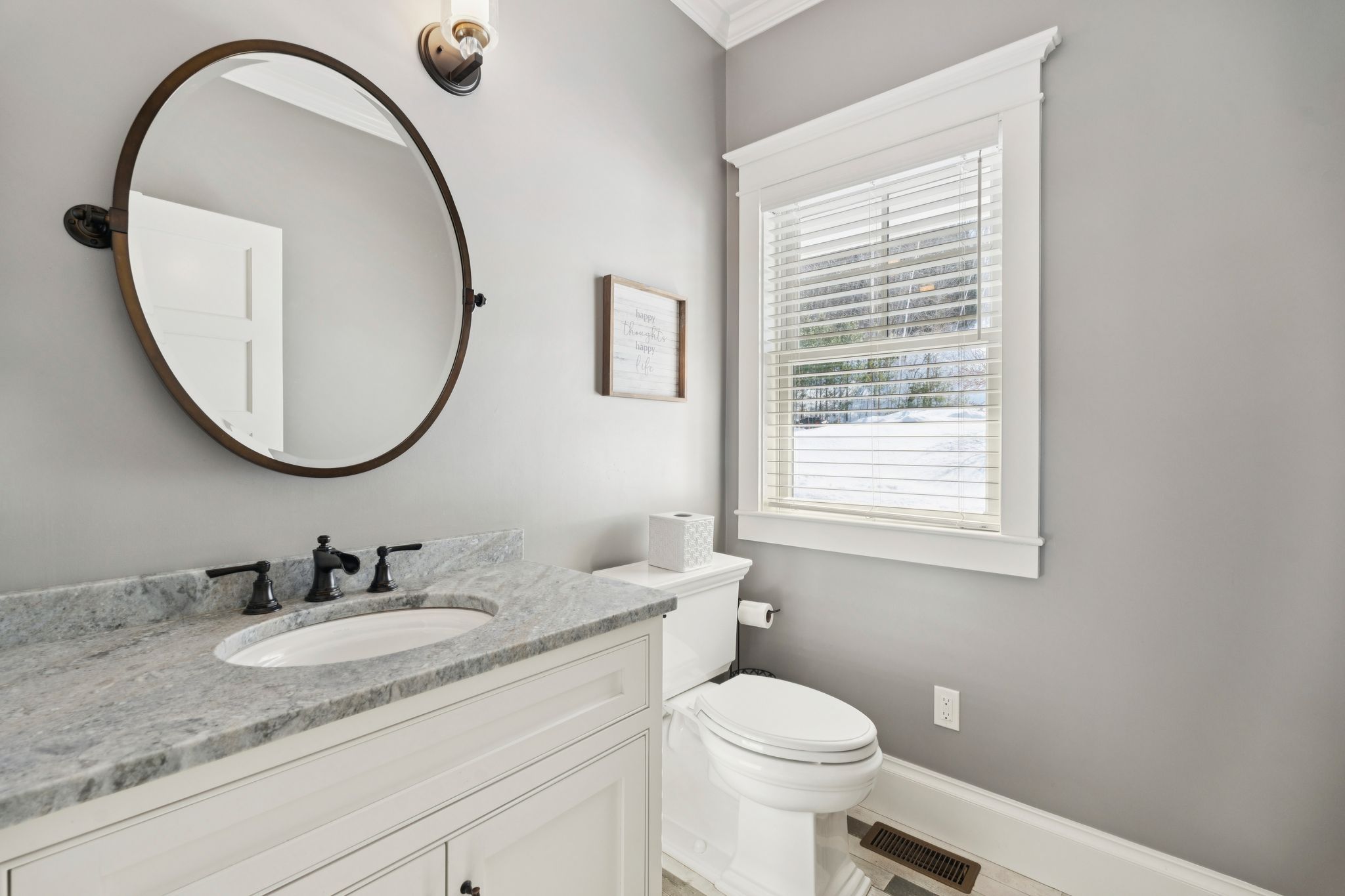 Relaxing bathroom with a white bathtub, decorative plants, beige tiles with a mosaic border, and a framed sailboat artwork on the wall