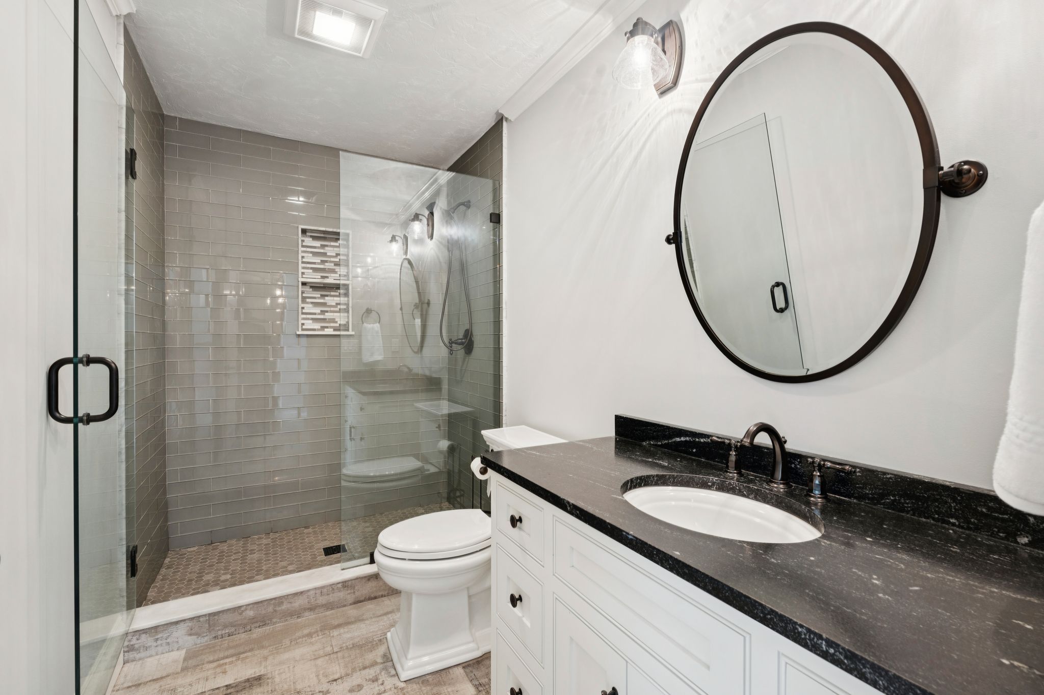 Bright and clean bathroom with a white vanity, potted plants, framed artwork, a window with a blue valance, and a shower with a white textured curtain.