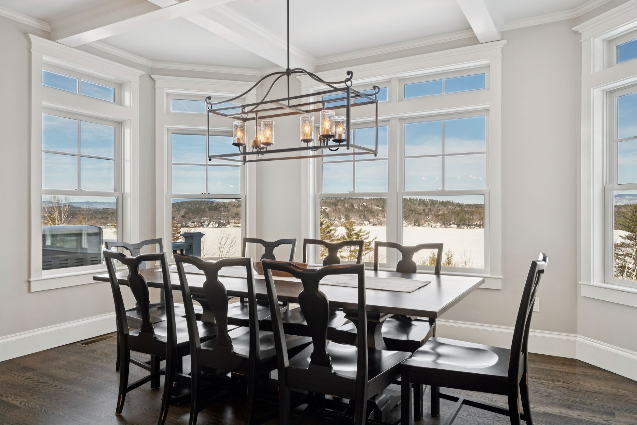 Bright and spacious modern kitchen with a large island, blue upholstered bar stools, stainless steel appliances, wooden cabinets, and large windows letting in natural light.