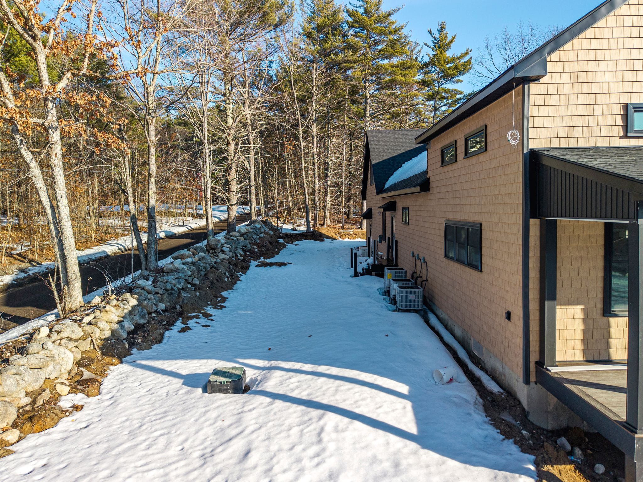 Aerial view of a lakeside property with multiple docks, surrounded by lush green trees and forested hills under a partly cloudy sky.