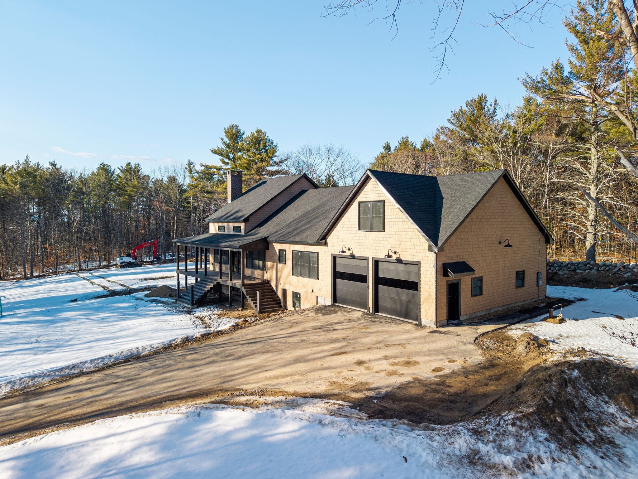 Aerial view of a lakeside home surrounded by lush green trees, with a private dock, boat, and boat lift on a calm lake in a suburban neighborhood.