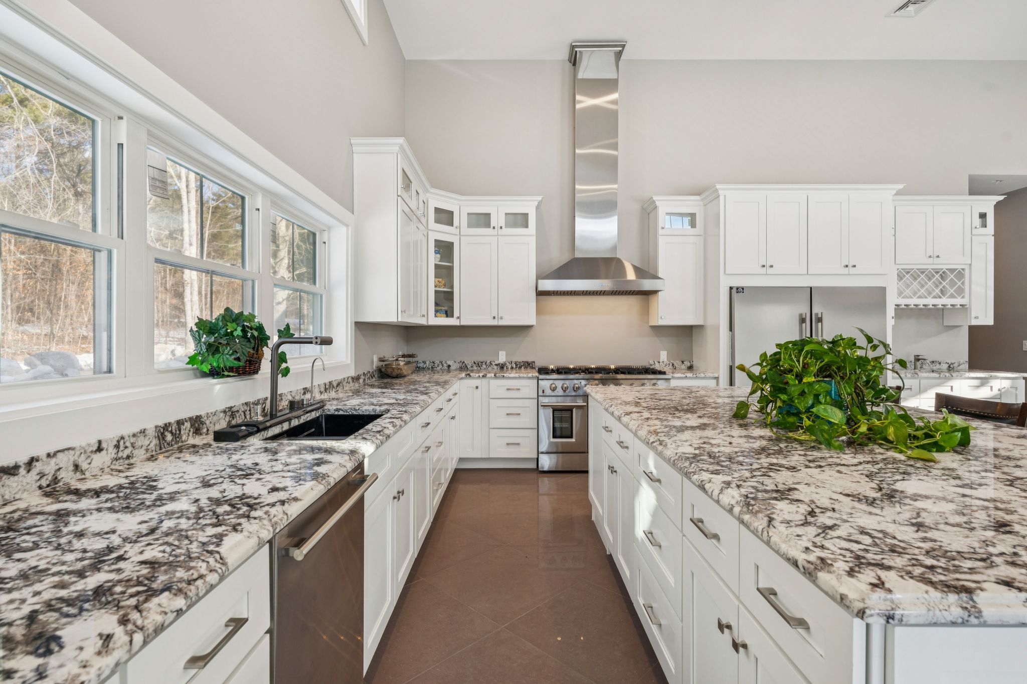 Living room with hardwood flooring, decorative area rug, staircase with wrought-iron banister, and a dining area in the background.