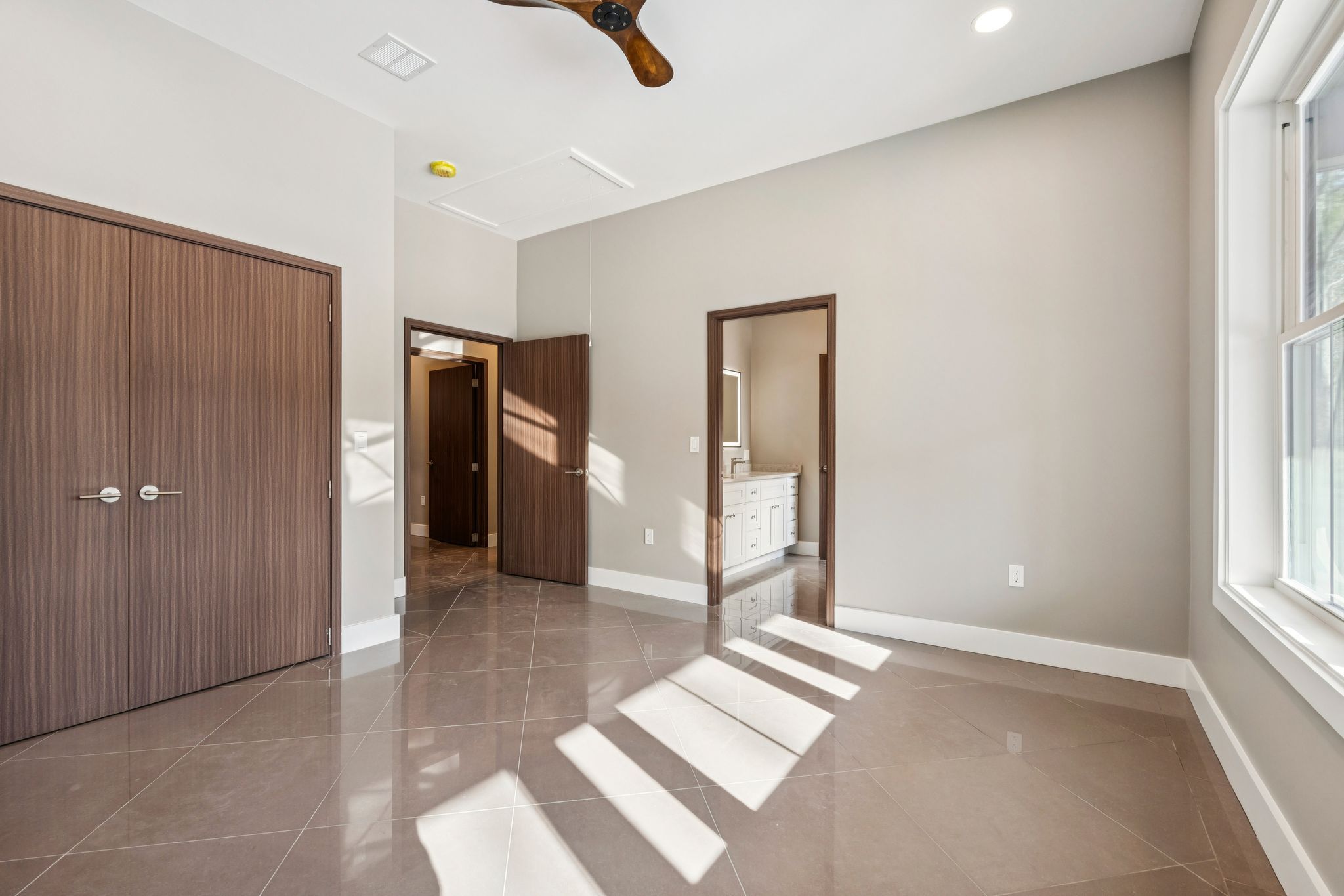 Bright and spacious white kitchen with granite countertops, hardwood floors, white cabinetry, stainless steel appliances, and large windows overlooking a snowy outdoor landscape