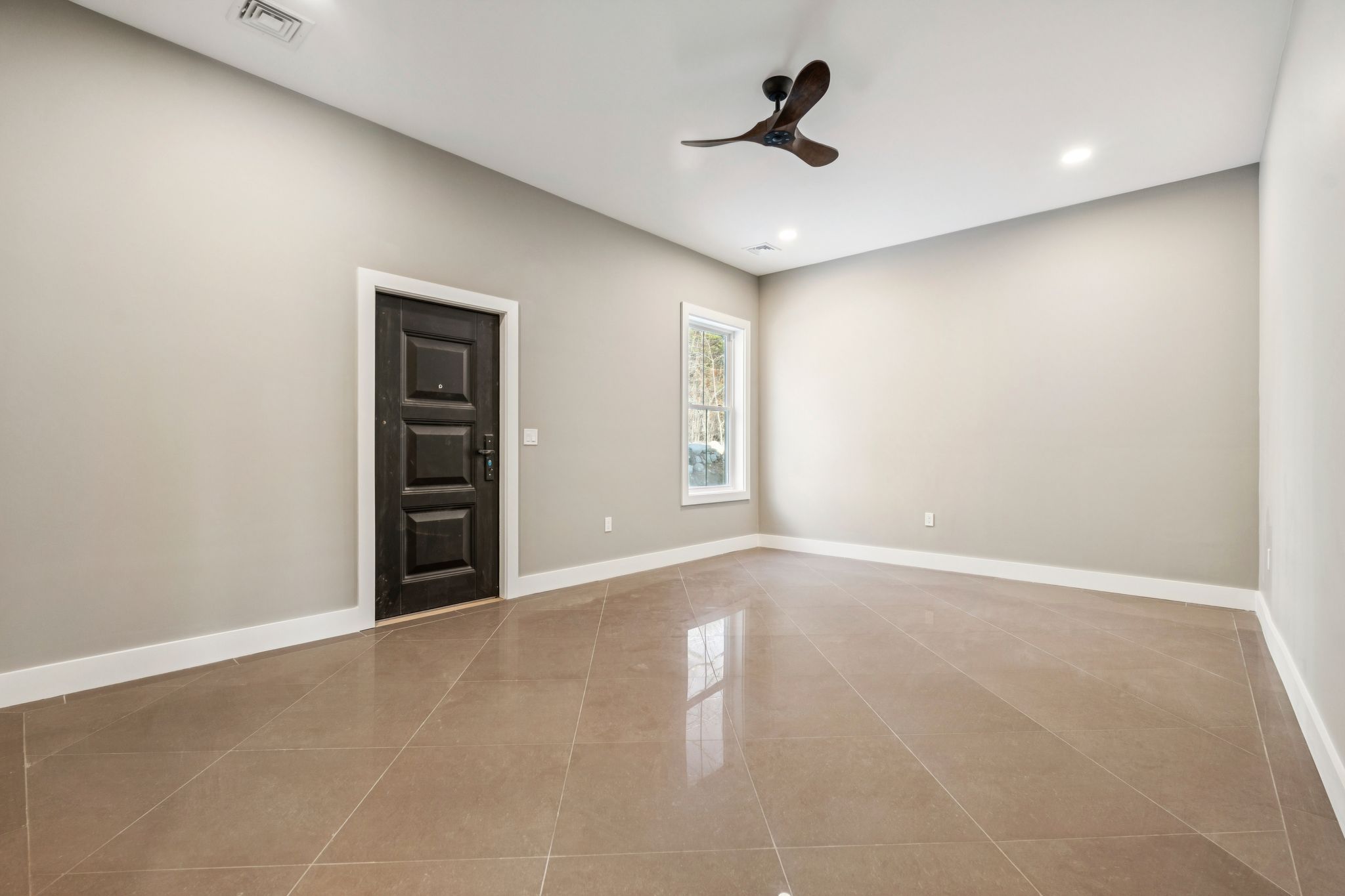 Elegant entrance foyer with white front door, wooden staircase with black wrought iron railing, decorative rugs, and rustic decor in a spacious home interior.