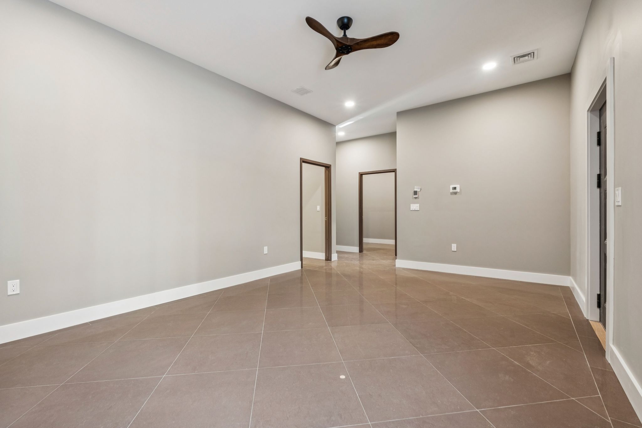 Bathroom with marble countertop, glass shower enclosure, and a bathtub with a marble surround, featuring a large window with blinds, framed artwork, and neutral-colored walls.
