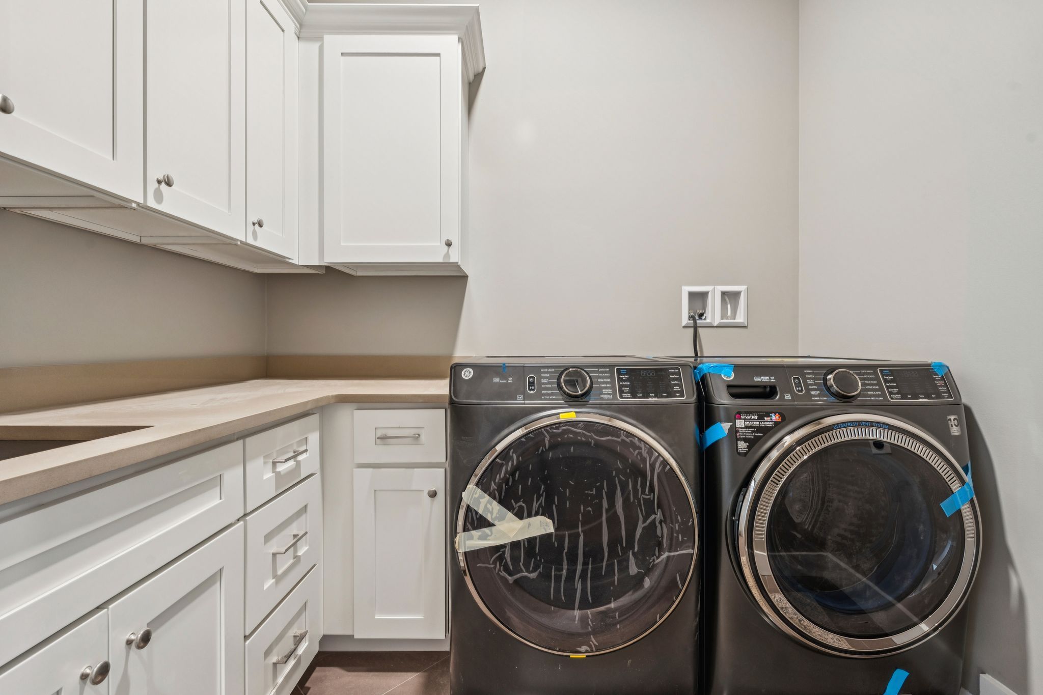 Elegant bathroom with floral wallpaper, gold-framed mirror, blue and white decorative elements, granite countertop, and neatly arranged towels and flowers.