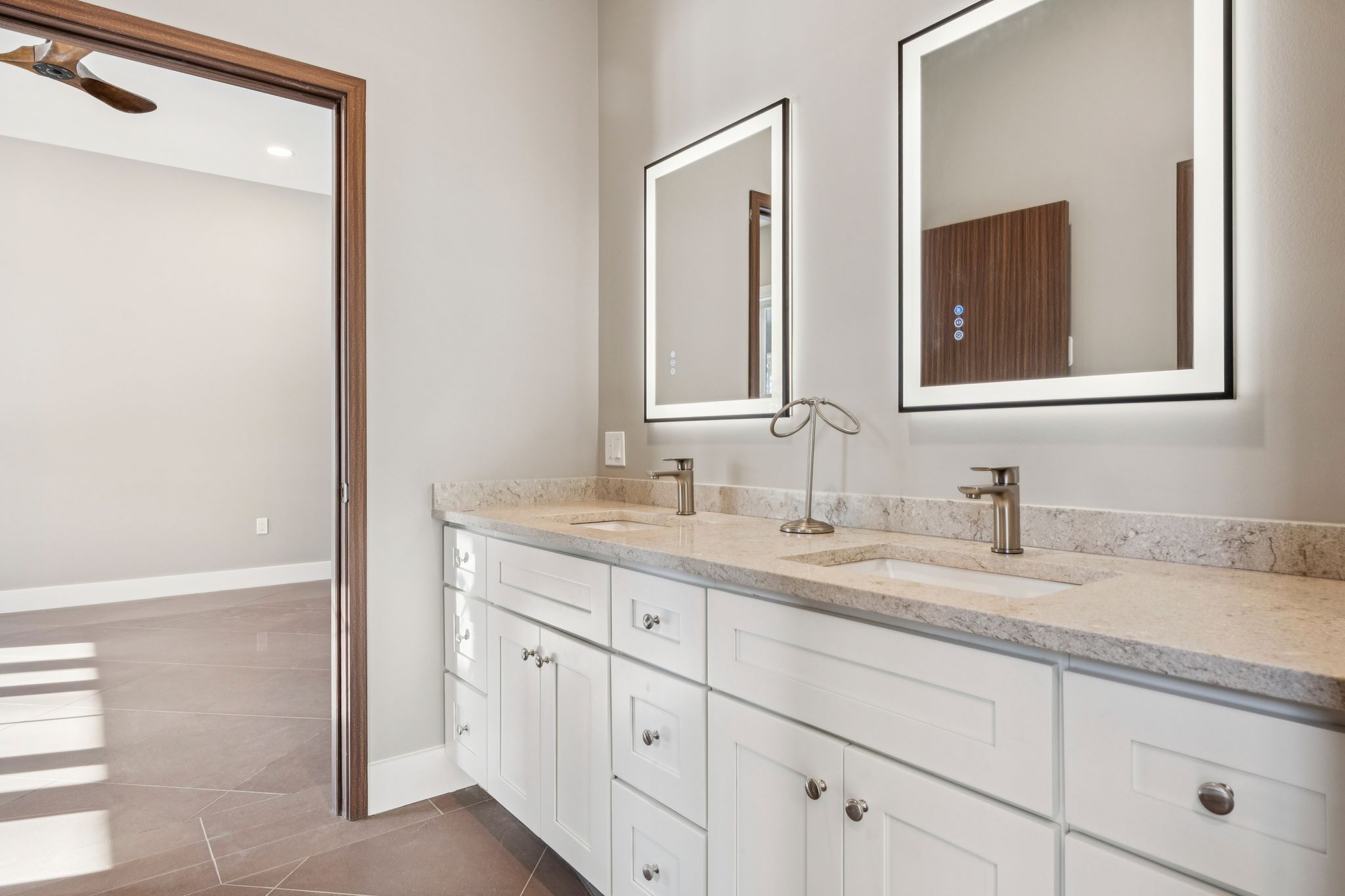 Bathroom with a white jacuzzi tub, framed wall art, decorative vase with flowers, window with blinds, and a patterned floor.