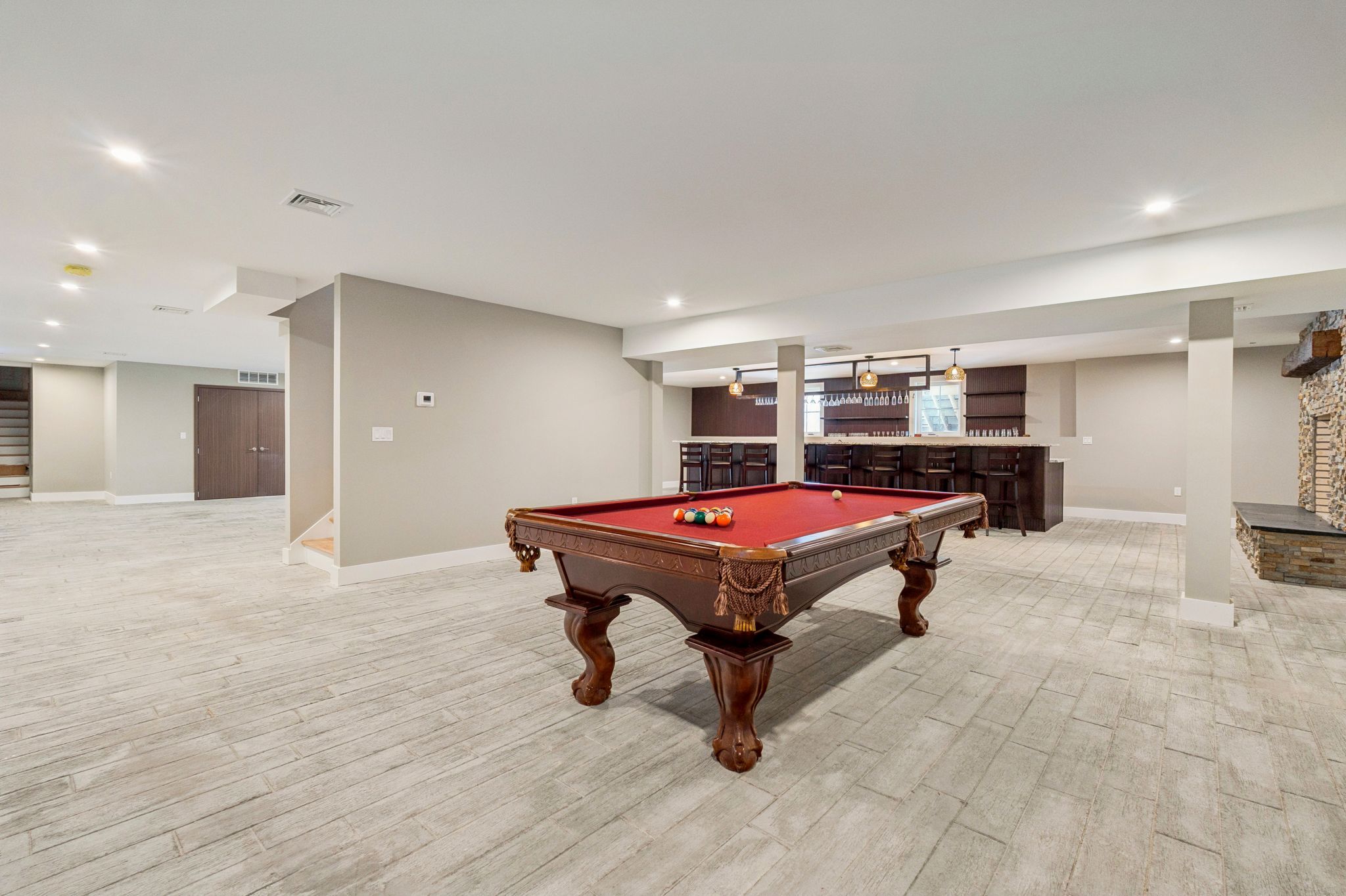 Spacious living room with large windows, leather sofa, wooden coffee table, recliner chair, built-in white cabinetry with decorative items, and carpeted flooring.