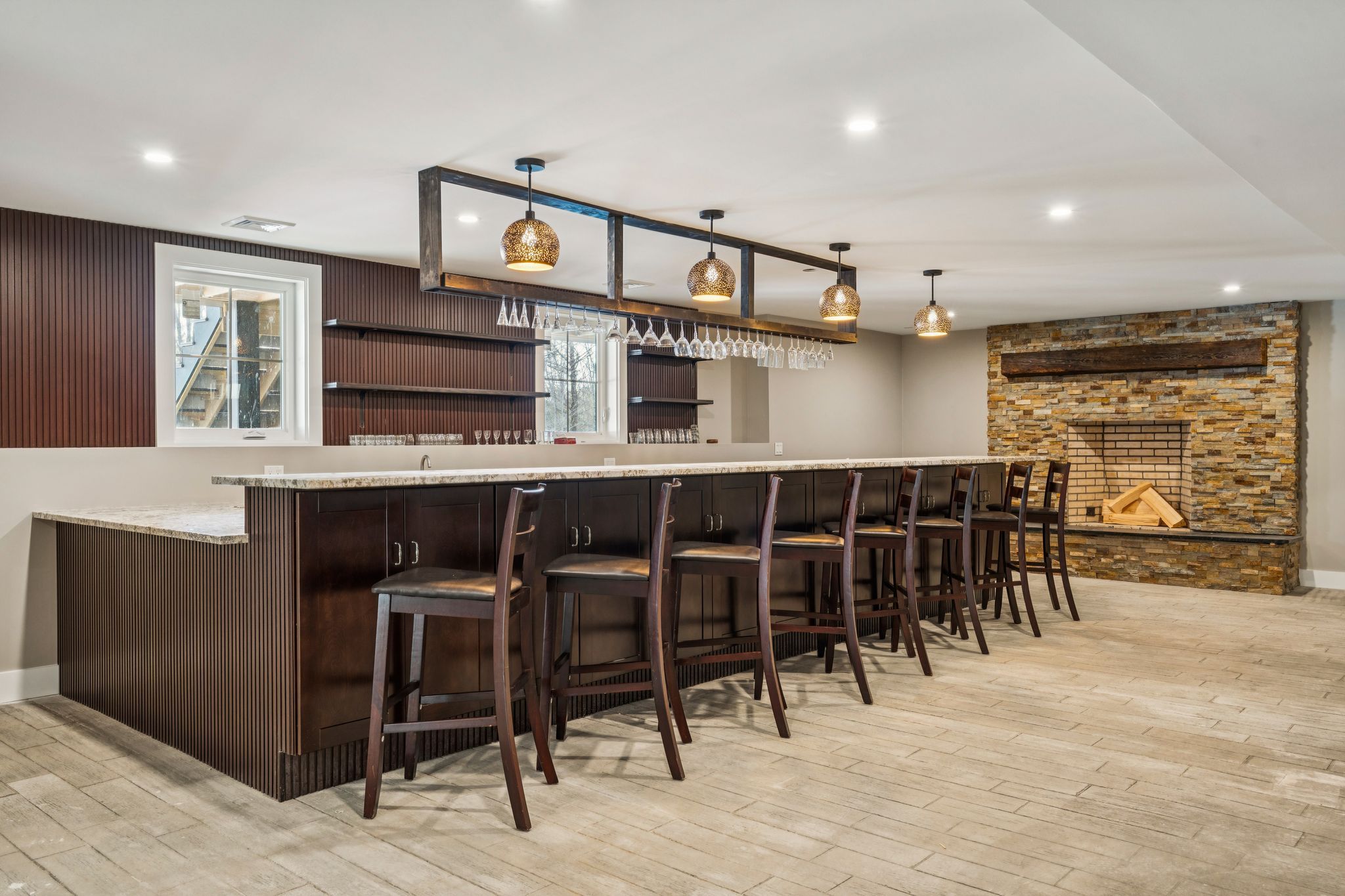 Cozy bedroom with wooden built-in wardrobe, large window overlooking a snowy lake and forest, and a bed with plaid quilt and matching pillows.