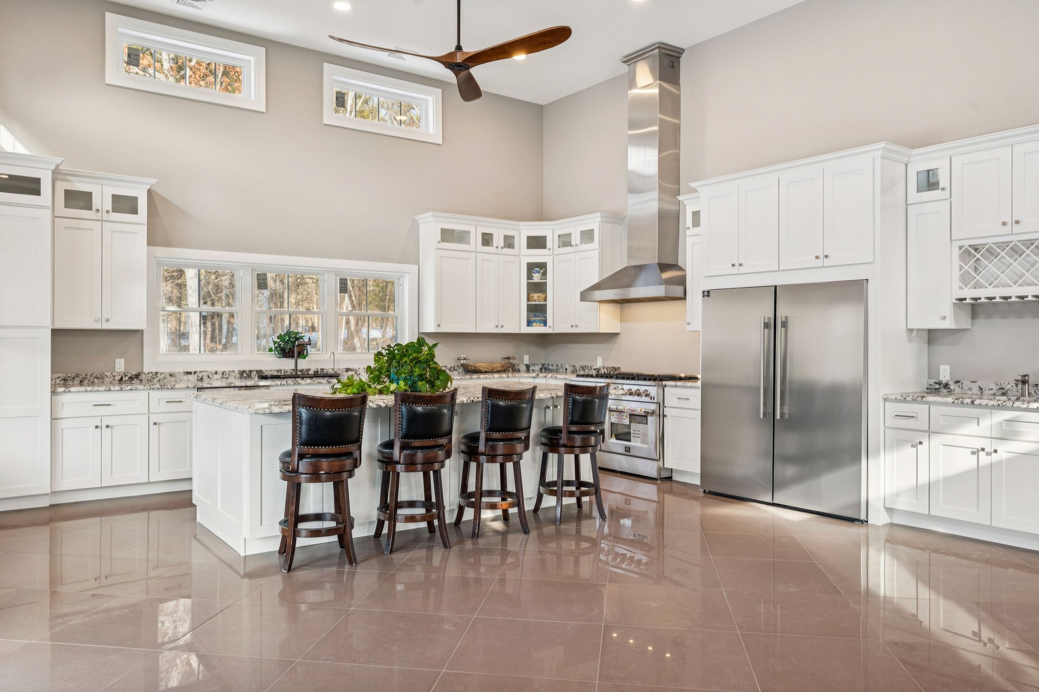 Elegant dining room with a white marble-topped table, high-back upholstered chairs, hardwood flooring, built-in white cabinets with glass doors, and decorative wall clock
